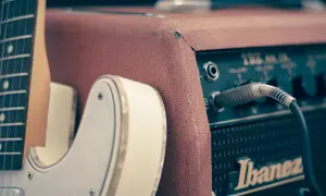 Biała gitara elektryczna podłączona do wzmacniacza Ibanez. Idealny zestaw do nauki gry na gitarze elektrycznej.