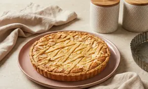 Une délicieuse tarte à la ricotta sucrée, garnie d'amandes effilées et d'une croisade de pâte dorée, prête à être dégustée.