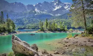 Türkisblaue Bergseen und schneebedeckte Gipfel – das sind die Attraktionen Bayerns. Ein Kajakfahrer gleitet über das klare Wasser.