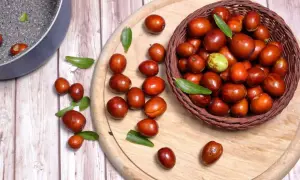 Giuggiole rosse e verdi in un cesto e sparse su un tagliere. Scopri quante calorie hanno le giuggiole per uno snack salutare.