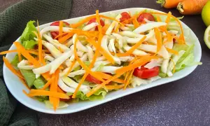 Deliziosa insalata di seppie con lattuga croccante, carote julienne e pomodorini freschi. Un piatto leggero e saporito.