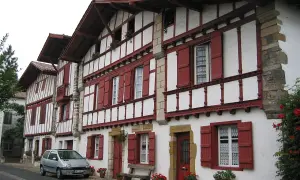 Maison basque typique, peut-être l'origine du nom Ithurburu. Volets rouges, colombages blancs, une voiture garée.
