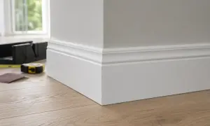Precyzyjne cięcie listew mdf pod kątem, by idealnie dopasować je do narożnika. Narzędzia do majsterkowania leżą obok.