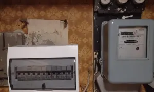 Stary licznik energii elektrycznej i nowoczesna rozdzielnica z bezpiecznikami, chroniąca przed przeciążeniem i zwarciem.