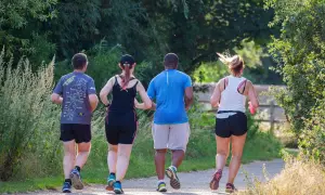 Quattro persone corrono su un sentiero. Ho perso 10 kg correndo, e loro sembrano motivati come me!