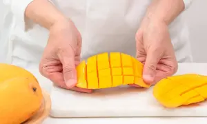 Ręce kroją mango na kostki. Czy koty mogą jeść mango? To pytanie nurtuje wielu właścicieli.