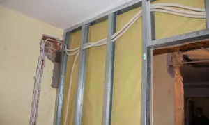 Nowa instalacja elektryczna bez kucia ścian. Widoczne profile metalowe, izolacja i nowe przewody w peszlach.