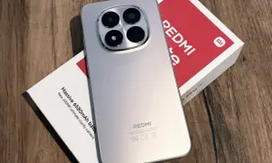 Srebrny, najnowszy Redmi z imponującym aparatem 200MP i baterią 6580mAh, leżący obok swojego czerwono-białego pudełka.