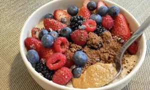 Schüssel mit overnight oats mit proteinpulver, Beeren, Kakao und Erdnussbutter.