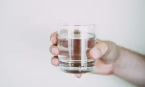 Dłoń trzyma szklankę wody. Prawidłowe nawodnienie, czyli picie wody, może pomóc w obniżeniu podwyższonej kreatyniny.