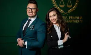 Para prawników w eleganckich garniturach na tle zielonej ściany z logo kancelarii.