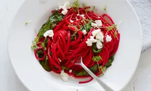 Rote-Bete-Spaghetti mit Spinat, Feta und Kresse auf einem Teller.