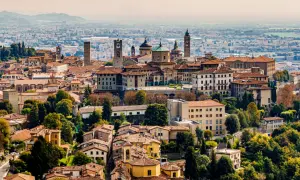 Panorama Bergamo, gdzie zobaczyć urokliwe kamienne wieże i zabytkowe budynki na tle zielonych wzgórz.