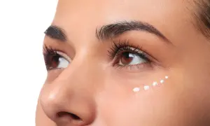 Application de crème hydratante en points sur le coin interne de l'œil pour un maquillage lumineux.
