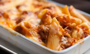 Un invitante piatto di pasta al forno, con penne ricoperte da un ricco sugo e abbondante formaggio fuso, pronto per essere gustato.