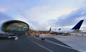 Flugzeuge am Flughafen Paris warten auf den Abflug. Ein modernes Terminalgebäude mit Glasfassade spiegelt den Himmel.