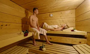 Ein Paar entspannt sich in einer Sauna. Vielleicht ist dies ein Teil eines **Bauernhofs in den Bergen**, wo man nach einem aktiven Tag in der Natur zur Ruhe kommen kann.