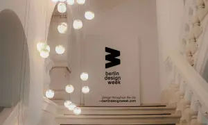 Eine Treppe mit Hängeleuchten und einem Banner für die **Berlin Design Week**.