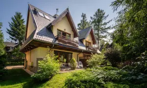 Urokliwy pensjonat w Zakopanem, z widokiem na Giewont. Dom otoczony zielenią, z drewnianymi balkonami i tarasem.