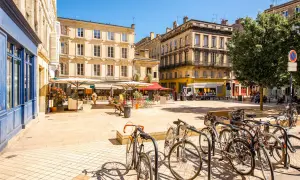 Sonniger Platz in Bordeaux mit Cafés, Fahrrädern und charmanten Gebäuden – ein echter bordeaux geheimtipp.