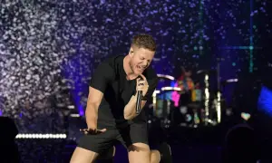 Imagine Dragons wokalista Dan Reynolds śpiewa z pasją na scenie, otoczony konfetti.