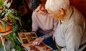 Un jeune homme et une personne âgée regardent un album photo.