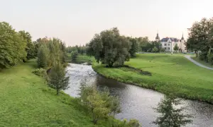 Idyllischer Flusslauf mit grünen Ufern und einem Schloss im Hintergrund. Ein perfekter Ort für Radwege Geheimtipp-Touren.