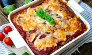 Herzhaftes Parmigiana di melanzane, überbacken mit geschmolzenem Käse und garniert mit frischem Basilikum.