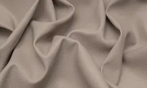 Miękka, beżowa eko skóra z delikatną fakturą, pofałdowana tworząc eleganckie draperie.