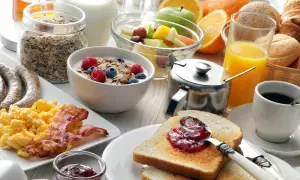 Ein reichhaltiges Frühstück in Görlitz: Rührei, Speck, Würstchen, Müsli, Obst, Toast mit Marmelade, Saft und Kaffee.