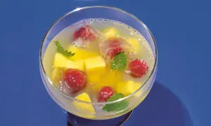 Erfrischende alkoholfreie Bowle mit Mango, Himbeeren und Minze in Eiswürfeln.