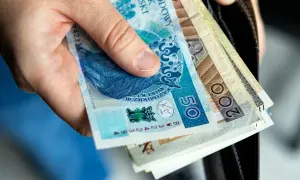 Dłoń trzyma polskie banknoty. Wkrótce jawność wynagrodzeń 2026, więc warto wiedzieć, ile zarabiamy.