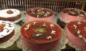 Deliziosi dolci in vetrina, tra cui un tortino con zucchero a velo e un invitante gelo di anguria decorato con fiori bianchi e scaglie di cioccolato.