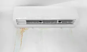 Condizionatore che perde acqua, lasciando macchie umide e colorate sul muro bianco.