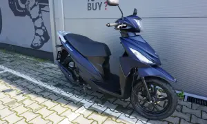 Elegancki, granatowy skuter Suzuki Address 110 zaparkowany na kostce brukowej.