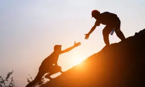 Siluetas de dos hombres ayudándose a subir una colina al atardecer. Un gesto de apoyo que contrasta con las frases de invalidación emocional.