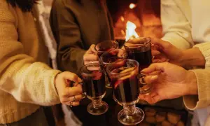 Ciepłe dłonie unoszą kubki z grzanym winem, przy kominku. Idealny wieczór z winem Bardolino.