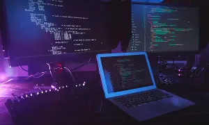 Code informatique sur plusieurs écrans, avec un clavier et un ordinateur portable. Le code Python utilise la méthode `strip` pour nettoyer les chaînes.
