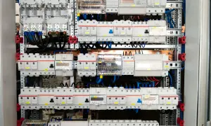 Panel elektryczny z licznymi wyłącznikami i zabezpieczeniami, połączonymi przewodami. Widać tu szyny elektryczne, które stanowią podstawę montażu.