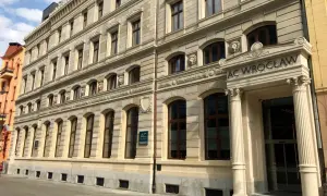 Elegancki budynek AC Hotel Wrocław z kamienną fasadą i ozdobnymi detalami.