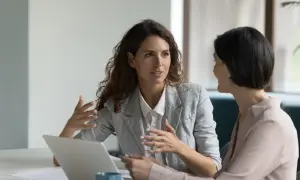 Due donne discutono di un mutuo senza ipoteca, con un laptop aperto sul tavolo.