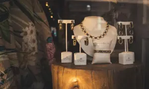 Elegancka biżuteria, w tym naszyjnik, bransoletka i kolczyki, prezentowana na drewnianym pniu. Złom złota w połączeniu z czernią tworzy luksusowy efekt.