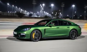Zielony Porsche Panamera GTS pędzi nocą po torze wyścigowym, oświetlonym jaskrawymi światłami.
