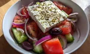 En fräsch grekisk sallad med fetaost, tomater, gurka, rödlök och oliver, toppad med örter.