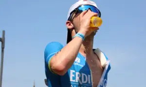 Triathlet trinkt bei heißem Wetter. Sport bei Hitze erfordert Flüssigkeitszufuhr.