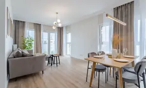 Nowoczesny salon z jadalnią. Szara kanapa, drewniany stół z krzesłami, ozdobna ściana i okna. Kto to? Flipper, bo tak nazywa się ten styl.