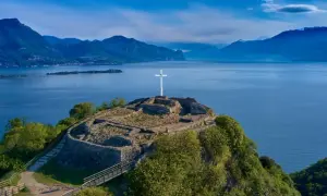Rovine di un castello con una croce bianca su una collina a Manerba del Garda. Vista panoramica sul Lago di Garda e le montagne.