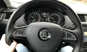 Blick auf das Lenkrad eines Autos mit Tachometeranzeige 55 km/h. Die Spurstange einstellen ist hier nicht direkt sichtbar, aber die Fahrt geht weiter.