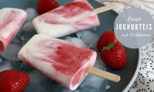 Eis selber machen schnell: Joghurt-Erdbeer-Eis am Stiel auf Eiswürfeln, garniert mit frischen Erdbeeren.