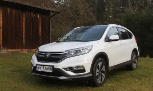Biały Honda CR-V 2.0 benzyna zaparkowany na trawie obok drewnianej stodoły.